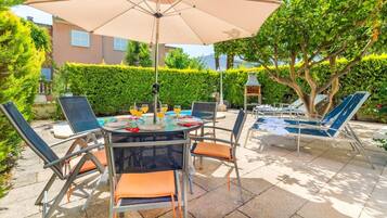 Een terras met een tafel, stoelen en een parasol.