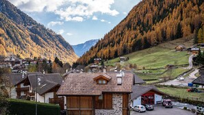 Un village de montagne avec des maisons traditionnelles en bois, un bâtiment en pierre doté d’une porte rouge et une vue dégagée sur les collines environnantes.