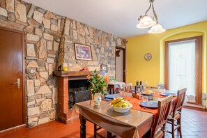 Comedor con pared de piedra, chimenea, mesa para dos personas y pared amarilla.