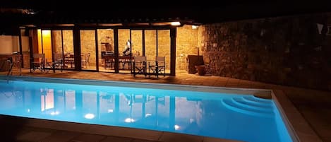 Una piscina amb mur de pedra i zona d'estar a l'aire lliure.