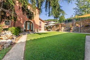 A well-maintained lawn, a stone wall, and a building with an arched entrance.