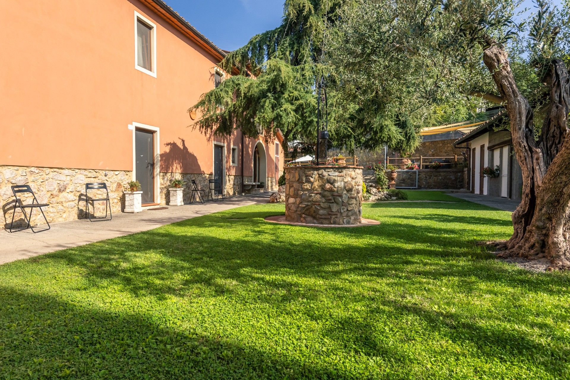 Un patio con una fuente de piedra, asientos al aire libre y un edificio con fachada de piedra.