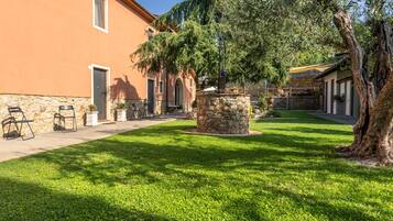 Un patio con una fuente de piedra, asientos al aire libre y un edificio con fachada de piedra.