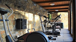 A covered outdoor gym area with exercise equipment, stone walls, and a wooden ceiling. - Villa 'Bella Toscana Relax' with Mountain View, Wi-Fi, and Air Conditioning (Monsummano Terme)
