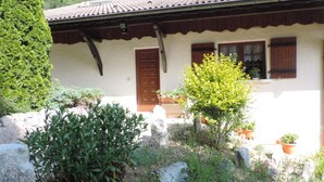 Il s’agit d’un bâtiment traditionnel, doté d’un toit en tuiles, d’une porte en bois et de plantes en pot dans le jardin.