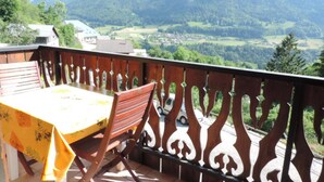 Un balcon avec une table et une chaise, donnant sur un paysage montagneux.