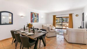 A dining area with a table set for four, a sofa, and a TV.