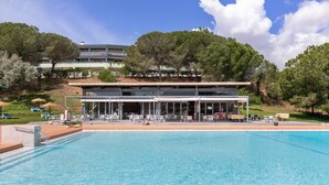 A swimming pool with a building in the background, surrounded by trees and a clear sky.