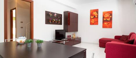 Una sala moderna con una mesa de comedor, un sofá rojo, obras de arte y un televisor.