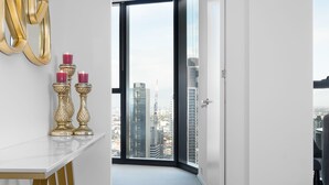 Ein modernes Interieur mit einer weißen Wand, einer goldenen abstrakten Skulptur und Blick auf die Stadt durch ein großes Fenster.