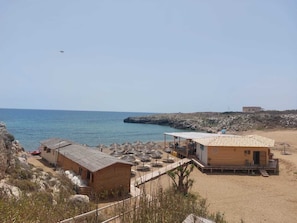 A coastal property with multiple buildings, a beach, and rocky terrain.