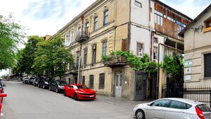 A street with parked cars, including a red sports car and a silver sedan. - HB apartments Mari Brose (Tbilisi)