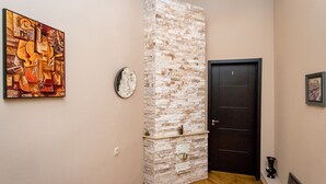 A hallway with a brick accent wall, a door, a framed picture, and a clock. - HB apartments Mari Brose (Tbilisi)