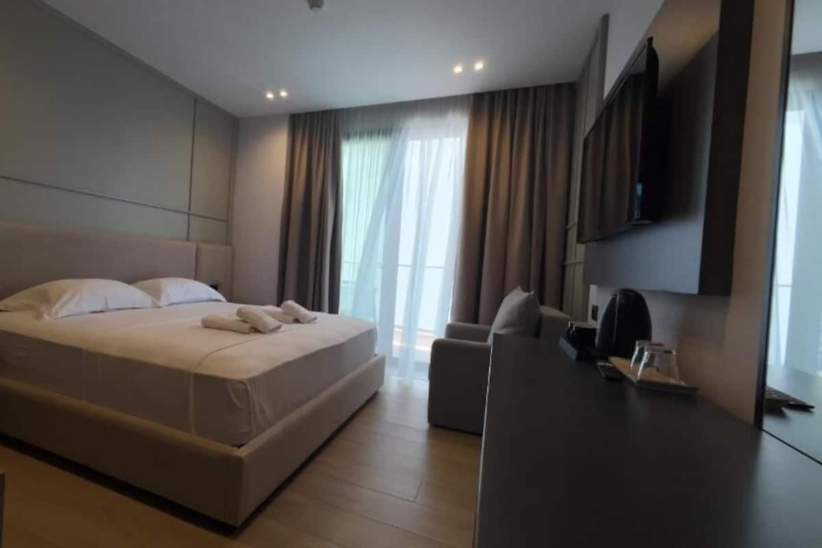 A modern hotel room with a large bed, a desk, and a TV mounted on the wall.