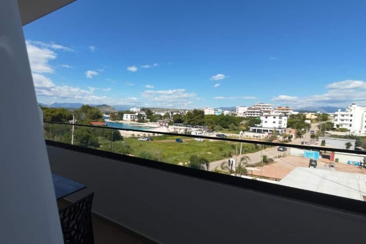A balcony with a view of a beach, buildings, and mountains.