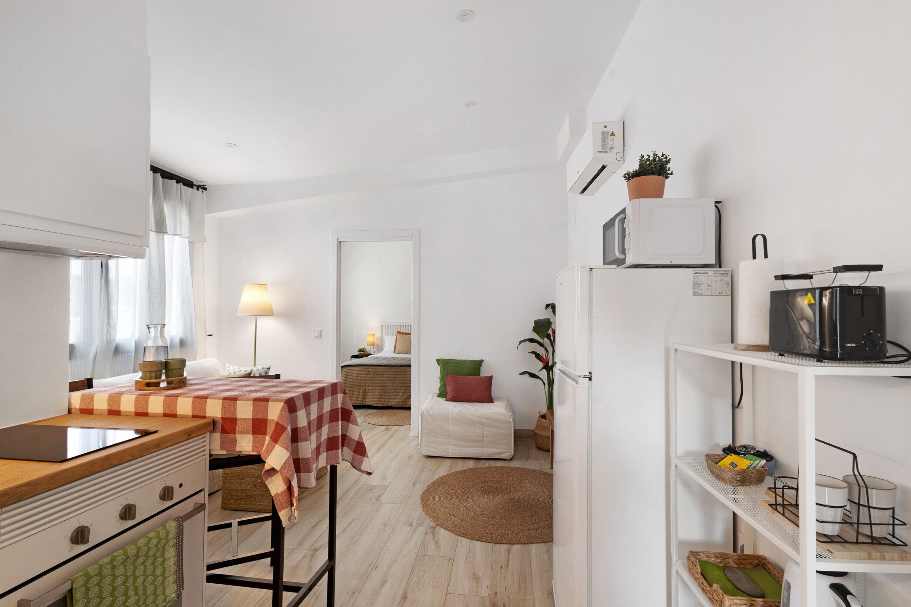 Una cocina moderna con mantel a cuadros, microondas, refrigerador y comedor con lámpara.