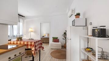 Una cocina moderna con mantel a cuadros, microondas, refrigerador y comedor con lámpara.