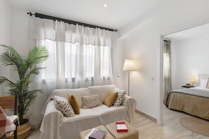 Una habitación con sofá, lámpara, planta en maceta y cama.
