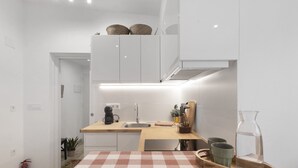 Una cocina moderna con armarios blancos, encimera de madera, un lavamanos y un felpudo de cuadros.