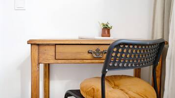 Un escritorio de madera con un cajón, una planta en maceta y una silla con cojín.