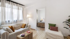 Una habitación con sofá, cama, lámpara y planta.