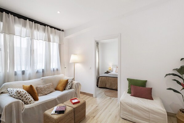 Una habitación con sofá, cama, lámpara y planta.