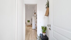 Un pasillo que conduce a un dormitorio con cama, mesita de noche y una planta en maceta.