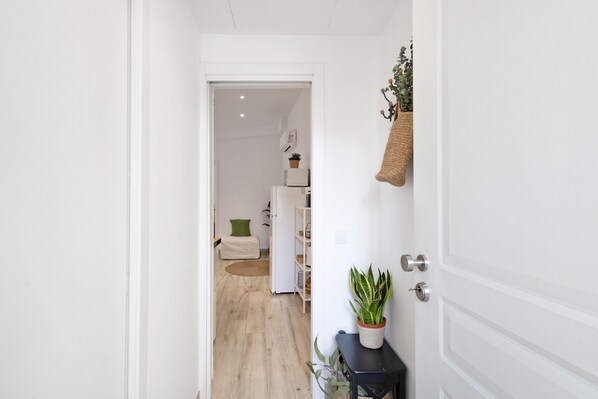 A hallway leading to a bedroom with a bed, bedside table, and a potted plant. - Apartment Privat Sant Celoni Montseny Barcelona with Balcony and Wi-Fi. (Sant Celoni)