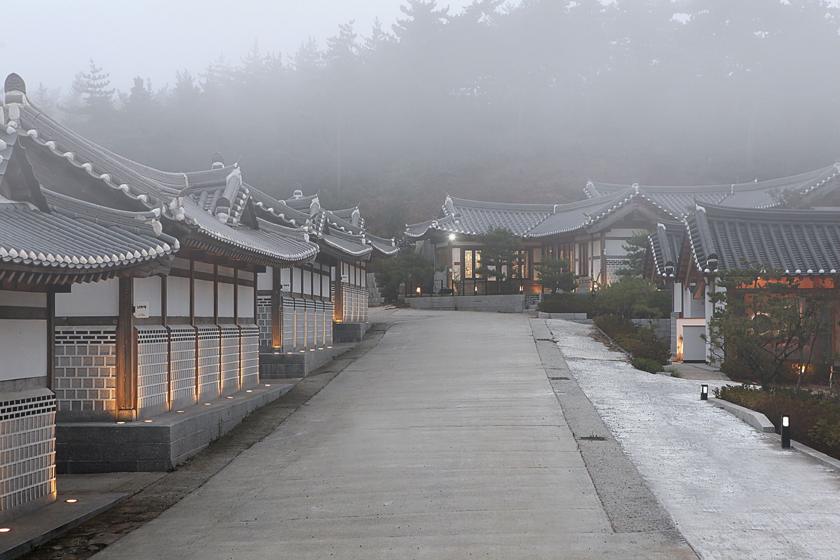 A traditional Korean-style building with tiled roofs and a long, straight pathway leading through it.