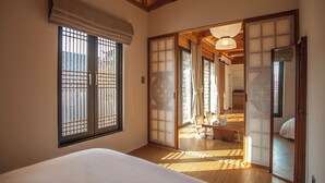 A traditional Japanese room with tatami flooring, a sliding door, and a bed with a white bedding.