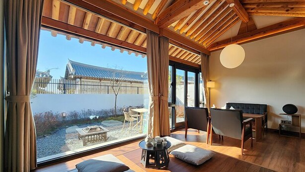 A modern room with a large window, wooden ceiling, and a traditional Japanese-style building in the background.