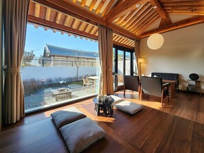 Ein moderner Raum mit großem Fenster, Holzboden und einem traditionellen japanischen Gebäude im Hintergrund.