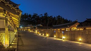 A traditional Japanese building with a wooden exterior and a tiled roof, illuminated by warm lighting.