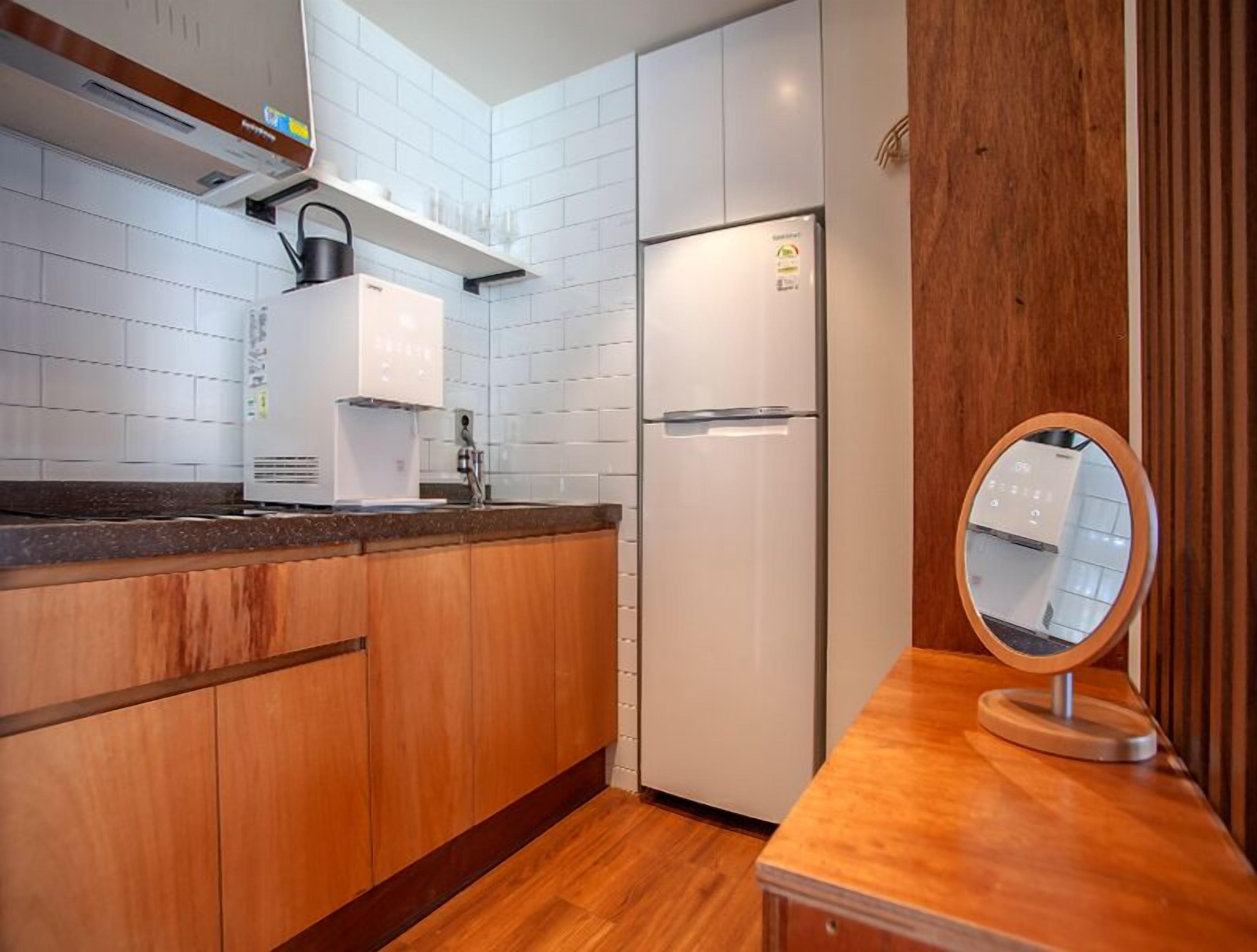 A modern kitchen with white cabinets, a built-in coffee maker, a refrigerator, and a wooden countertop.