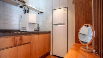 A modern kitchen with white cabinets, a built-in coffee maker, a refrigerator, and a wooden countertop.
