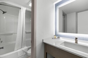 Ein modernes Badezimmer mit einer Badewanne, einer Dusche und einem großen Spiegel über dem Waschbecken.