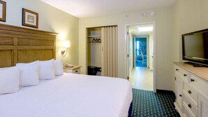 A hotel room with a large bed, a television, a dresser, and a bathroom visible through an open door. - Enchanting Oceanfront Suite with Views 3rd Floor (Myrtle Beach)
