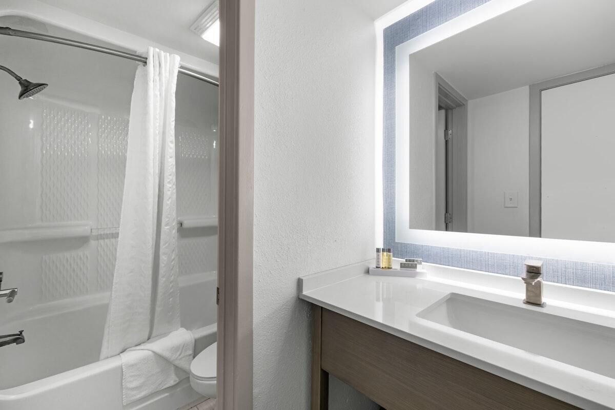 Un baño moderno con bañera, ducha y un espejo grande sobre el lavamanos.