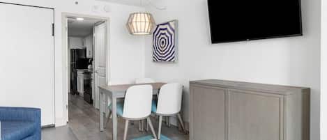 A modern living room with a TV, dining table, chairs, and a cabinet.