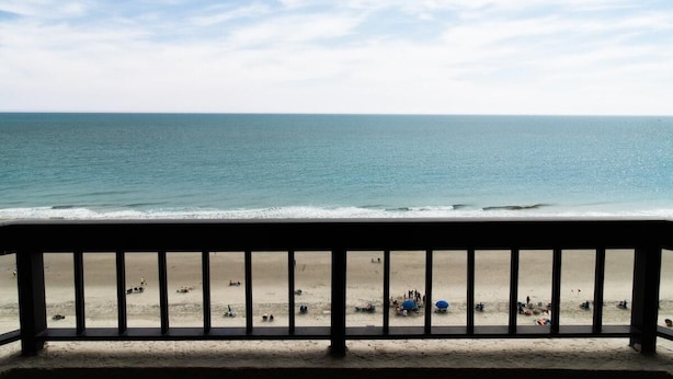 A beach view from a balcony with a railing, sandy beach, and ocean. - Seaside Tranquility Suite Stunning Views 11th Flr! (Myrtle Beach)