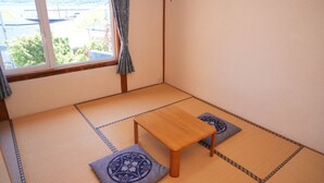 Um espaço com tatames, uma mesa de madeira e dois almofados.