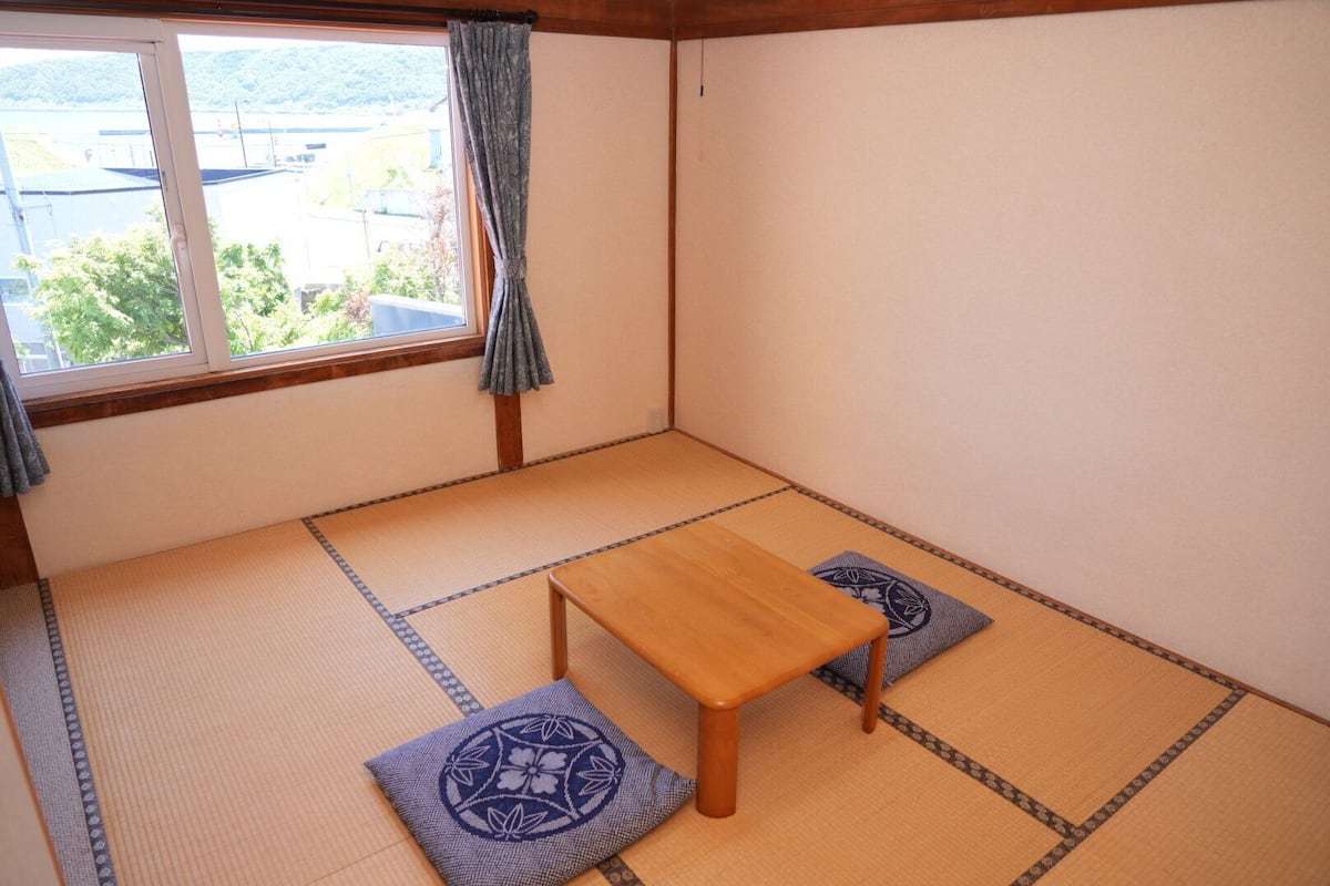 Una habitación con esteras de tatami, una mesa de madera y dos cojines.