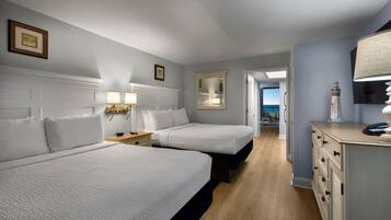 Une chambre d’hôtel avec deux lits, des lampes de chevet, une commode, un miroir et une vue sur l’océan.