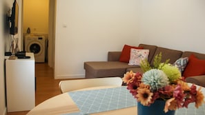A living room with a sofa, a coffee table with a geometric-patterned table runner, and a vase with flowers.