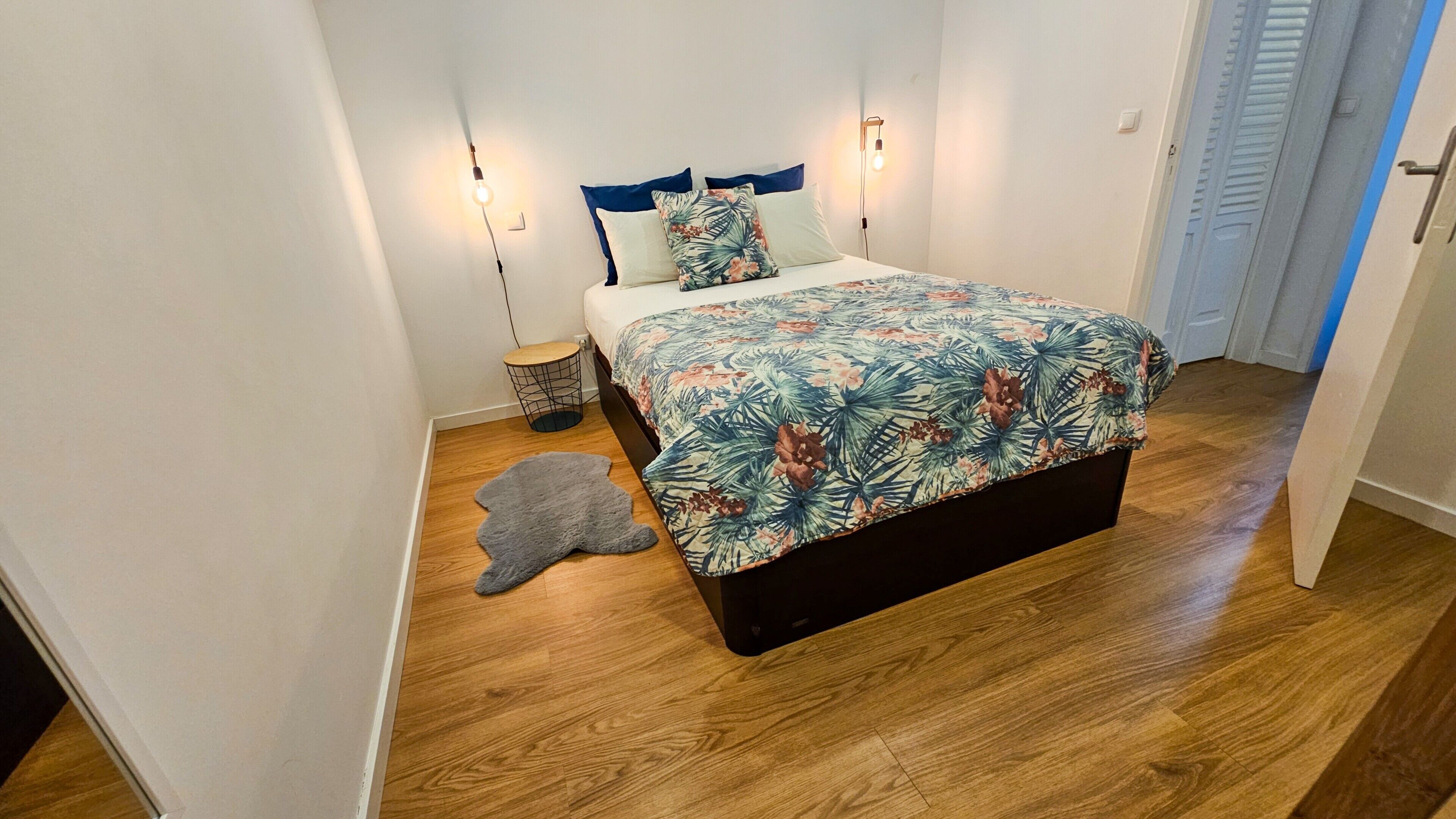 A bedroom with a bed, a nightstand, a lamp, and a rug.