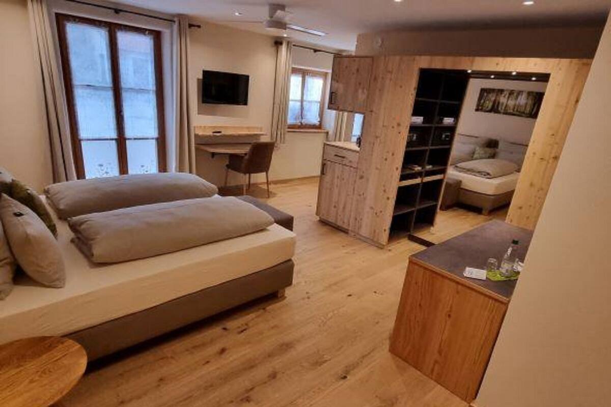 Ein modernes Zimmer mit einem großen Bett, einem Holztisch, einem Fernseher und einer Sitzecke mit einem kleinen Tisch.