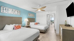 A hotel room with two beds, a ceiling fan, a TV, and a view of the ocean. - Seaside Tranquility Spacious Suite 5th Floor (Myrtle Beach)