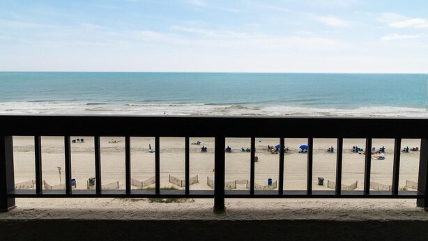 A beach view from a balcony with a railing, sandy beach, and ocean. - Enchanting Seaside Oceanfront Suite 6th Floor (Myrtle Beach)