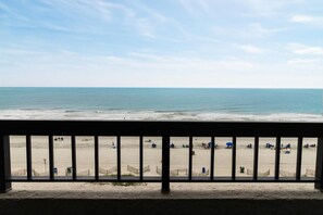 Vista sulla spiaggia dal balcone, con ringhiera, spiaggia sabbiosa e oceano.