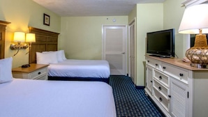 Une chambre d’hôtel avec deux lits, une télévision, une commode et une lampe.